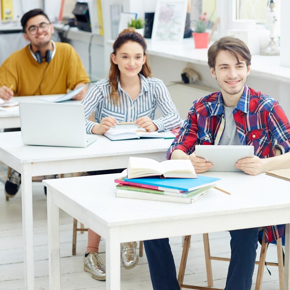 Group of college learners sitting by desks at lesson